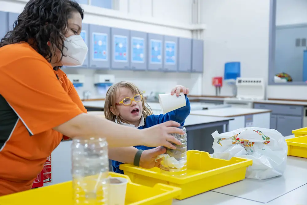 Little girl taking part in a hands on experiment with ASC team member helping