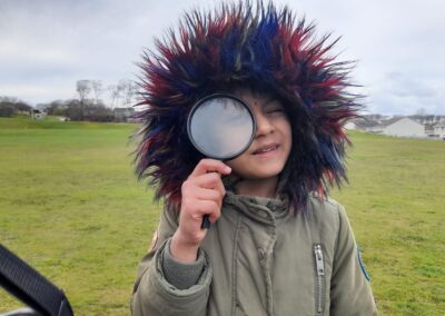 child holding up a magnifying glass to their eye